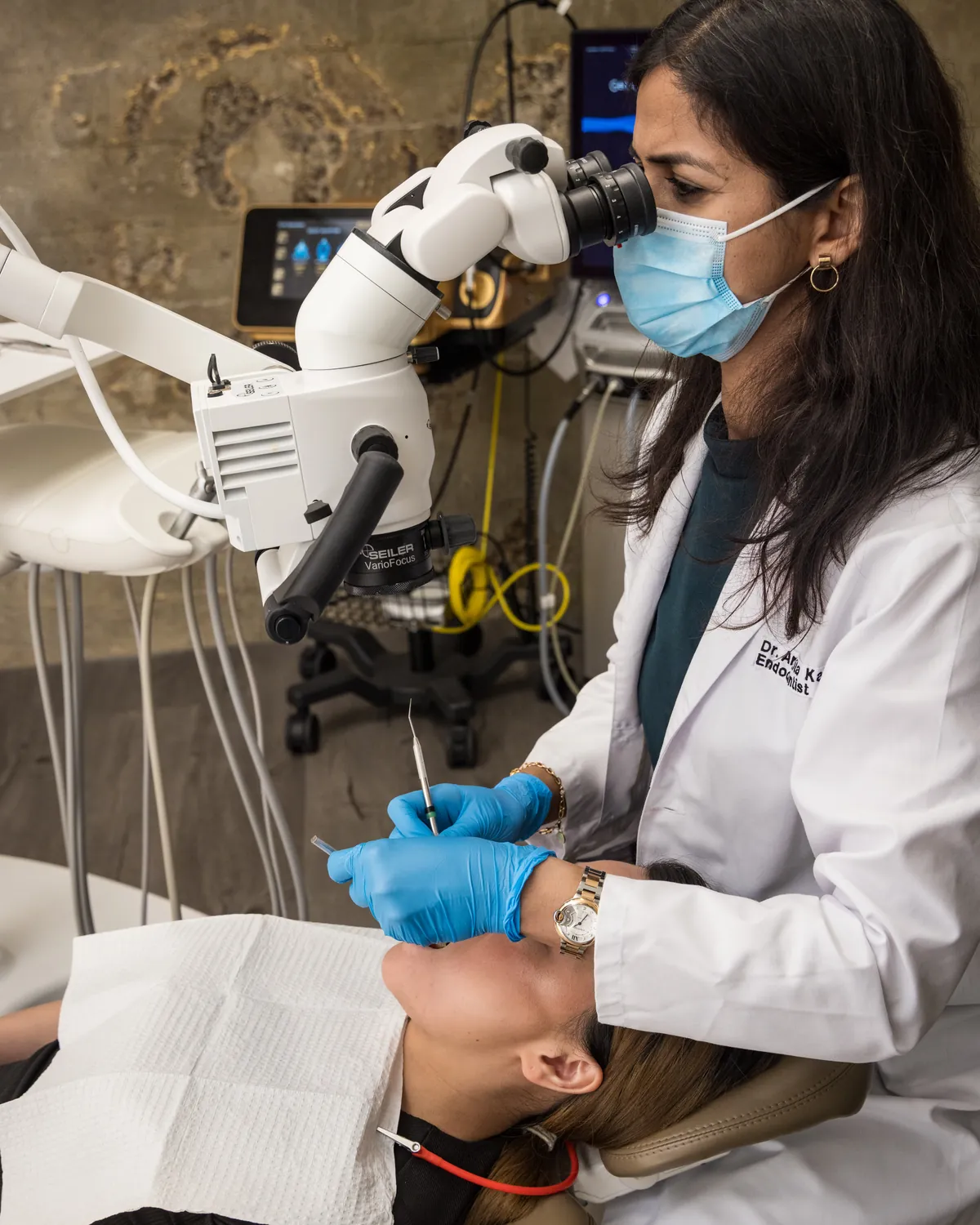 Dr. Ankita Kathpalia examining a patient's tooth through a dental operating microscope at Endospecialists