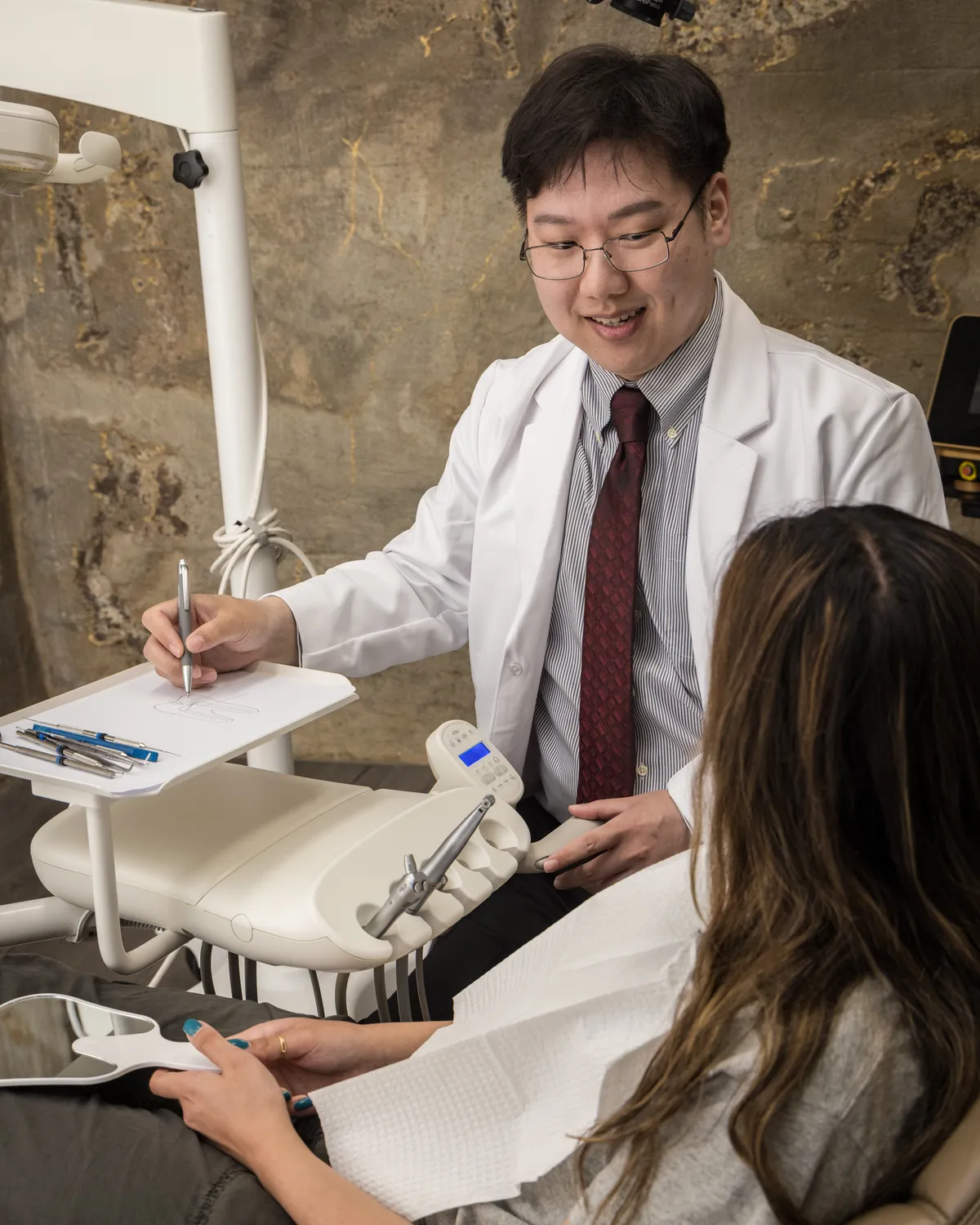 Dr. Sean Kim sketches a diagram of a tooth while explaining root canal treatment to a patient at Endospecialists